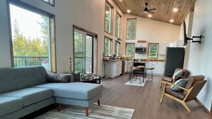 A spacious living area with a sofa, a chair, a rug, and a kitchen in the background. - Charming 2-bedroom in delightful Seward with WiFi. Not kidding friendly (Seward)