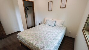 A bedroom with a bed, a wardrobe, and a framed picture on the wall. - Charming 2-bedroom in delightful Seward with WiFi. Not kidding friendly (Seward)
