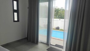 Ein Zimmer mit Schiebetür zum Poolbereich, einem kleinen Fenster und einer Fußmatte.