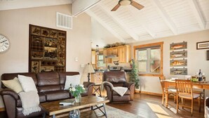 A spacious living room with a brown leather sofa, a coffee table, and a dining area with wooden chairs. - *NEW*  Alpine Crest + Pet Friendly (Big Bear Lake)