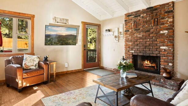A cozy living room with a fireplace, a couch, a coffee table, and a painting on the wall. - *NEW*  Alpine Crest + Pet Friendly (Big Bear Lake)