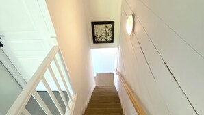 A staircase with a wooden handrail, carpeted steps, and a light fixture on the wall. - T3 curiste rental 600m from the spa (Eugénie-les-Bains)