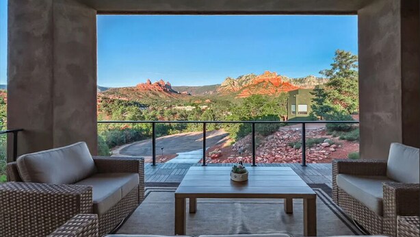 A balcony with wicker furniture and a view of red rock formations. - NEW Spacious 5-bedroom house with Views, Spa, Fire pit, Golf & Hammocks (Sedona)