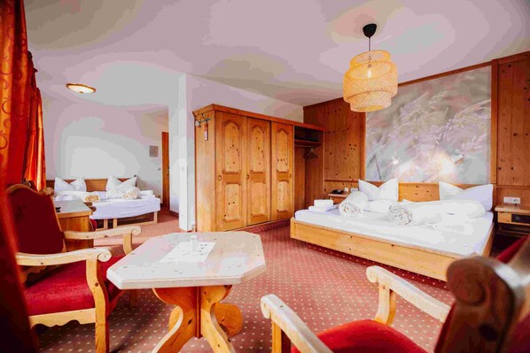 Une chambre d’hôtel avec deux lits, une armoire en bois, une table à manger et un grand tableau accroché au mur.