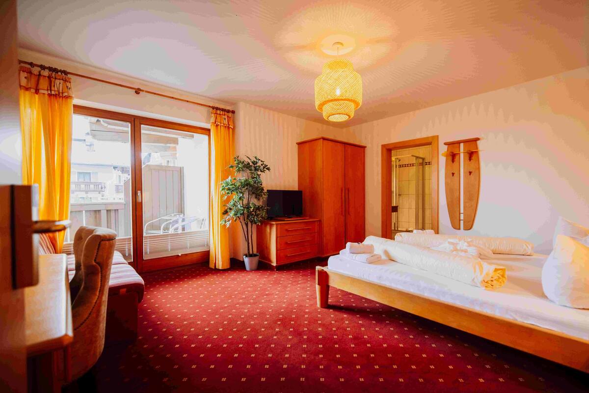 A hotel room with a bed, a desk, a chair, a television, and a large window with curtains.