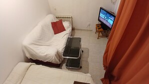 A small, sparsely furnished room with a bed, a small table, a television, and a radiator. - Room-double Room With Air Conditioning i (Toledo)