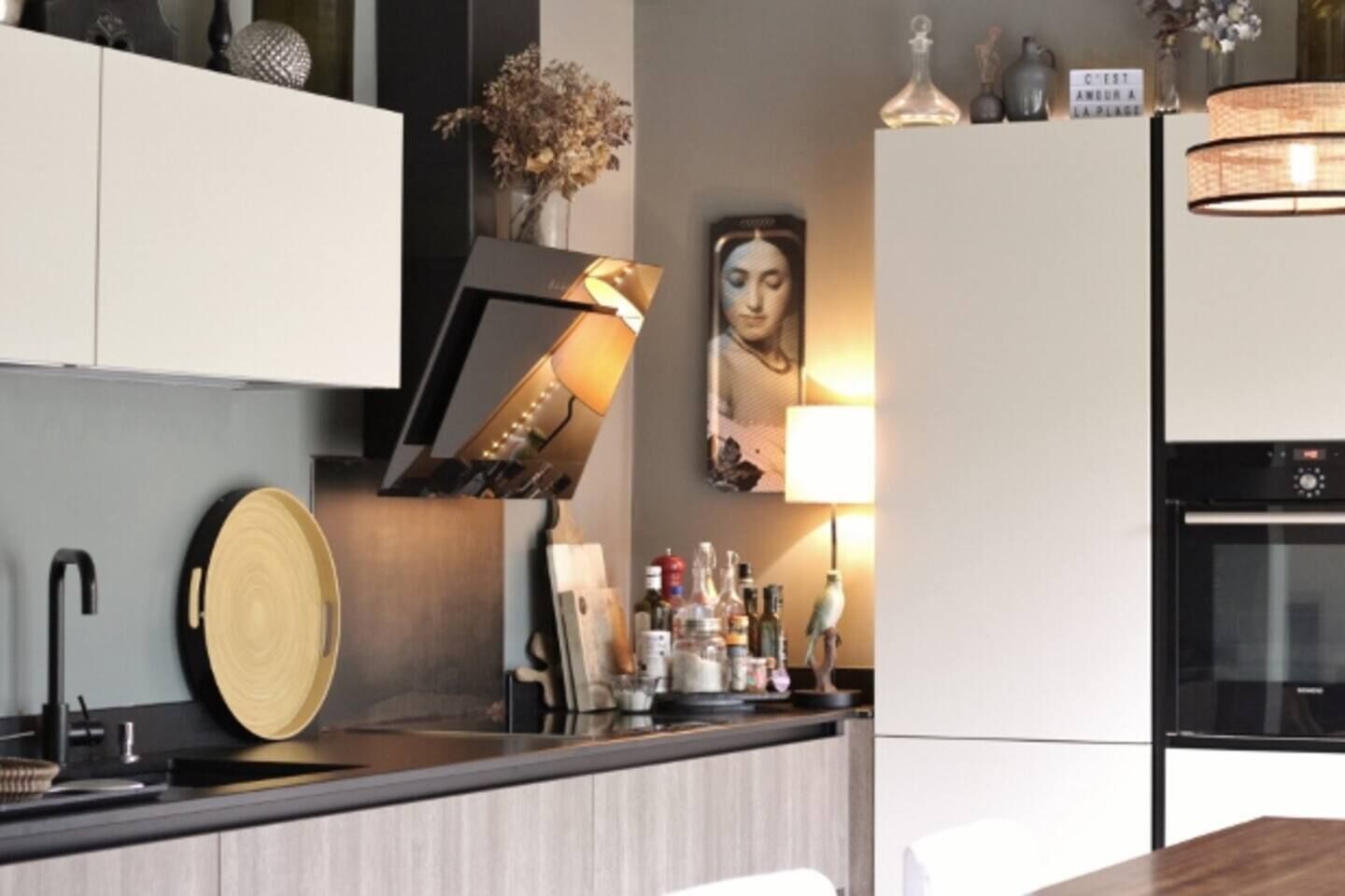 A modern kitchen with a built-in oven, a sink, and a countertop with various items.