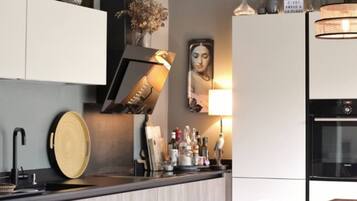 A modern kitchen with a built-in oven, a sink, and a countertop with various items.