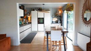 A modern kitchen with a dining area, wooden flooring, and a large window. - Maison Piscine in Bidart (Unknown)