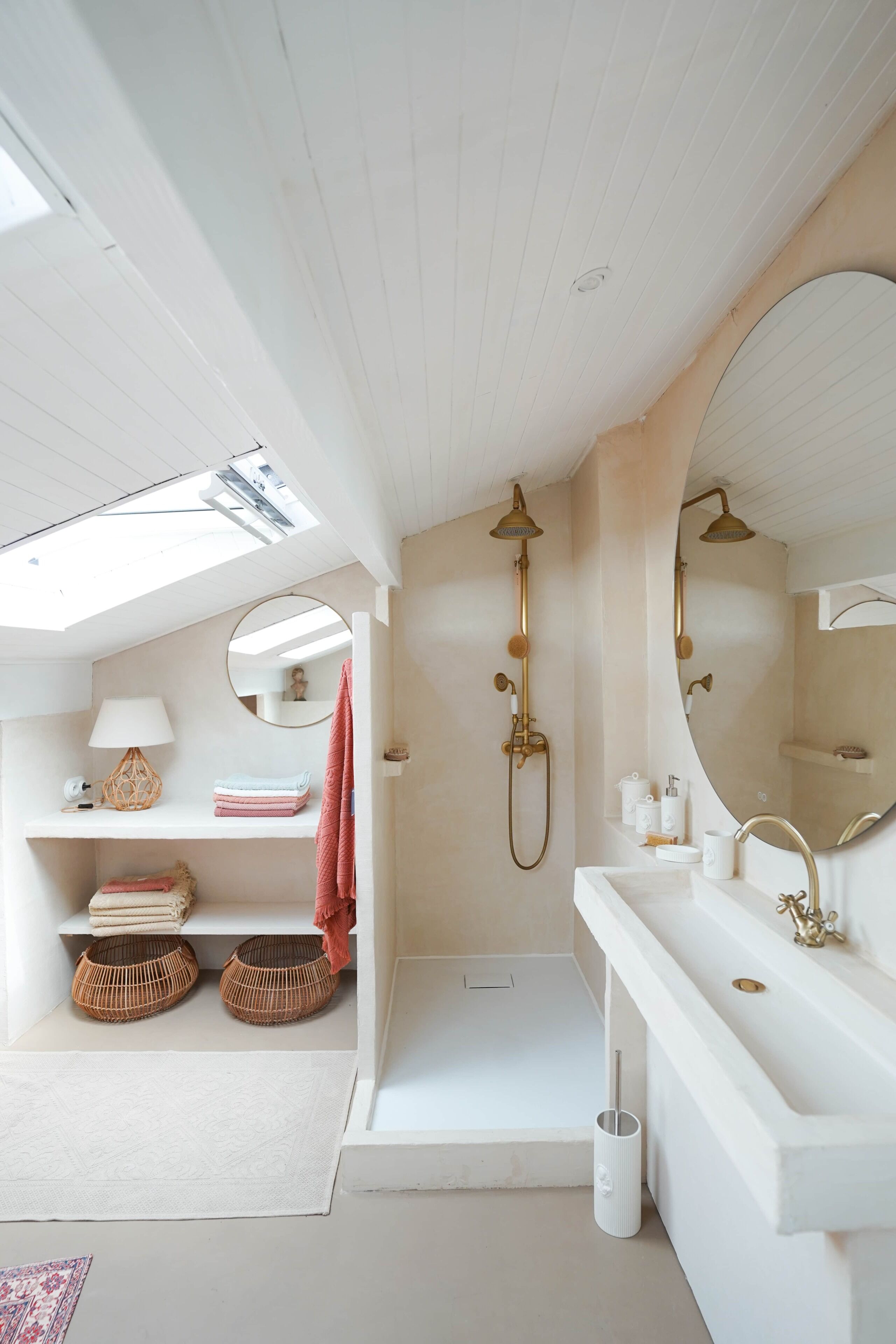 Un baño moderno con tragaluz, una bañera independiente, un espejo grande y un mueble de tocador blanco.