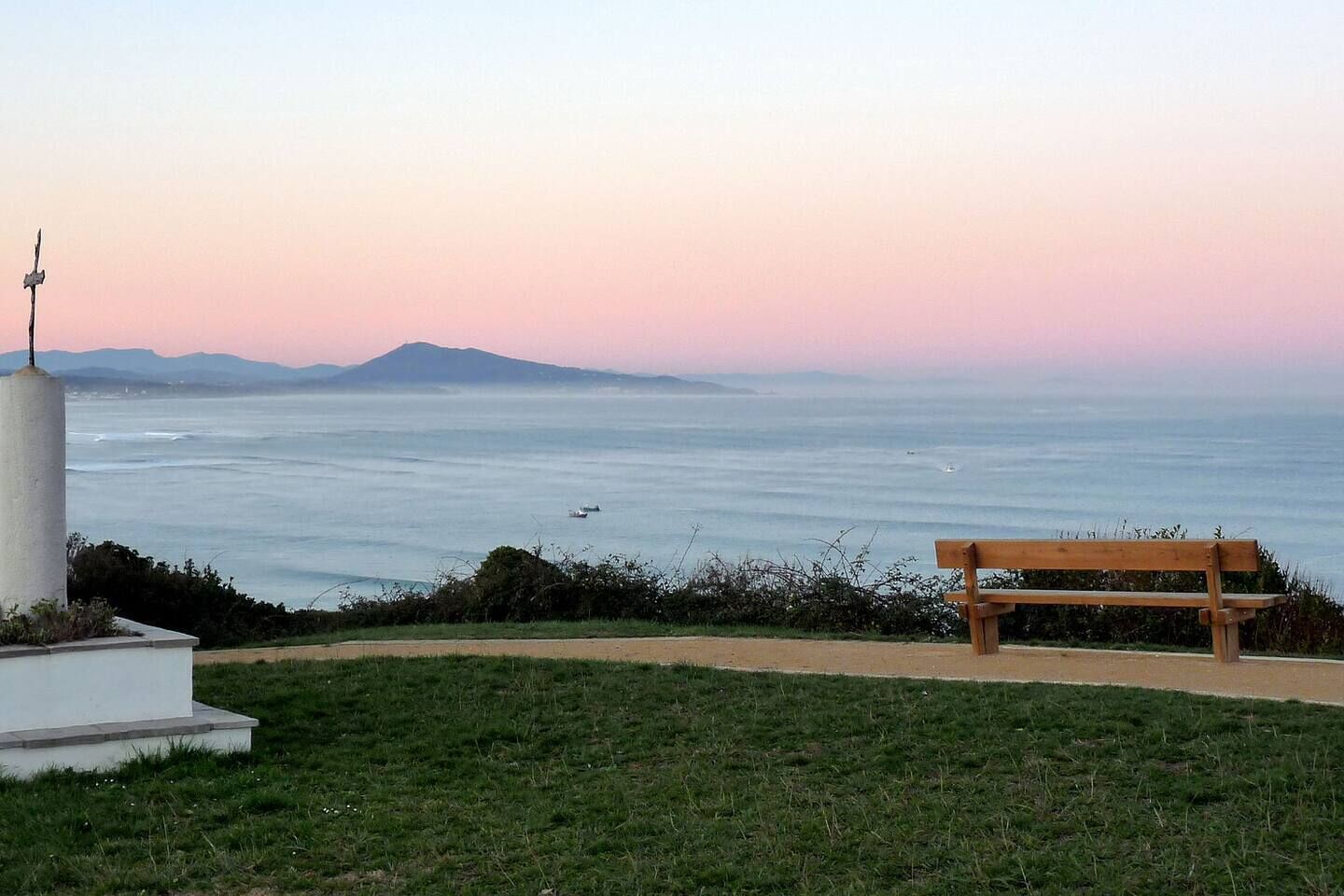 Un banc offrant une vue sur la côte, avec un monument au premier plan.