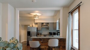 A modern kitchen with a central island, bar stools, and a view of the living area. - Modern 2 Bedroom Downtown Apartment (Milwaukee)
