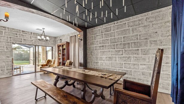 Una habitación amplia con un gran comedor de madera, un banco y una estantería.