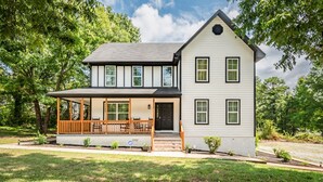 Een twee verdiepingen tellend huis met een overdekte veranda en een kleine voortuin.