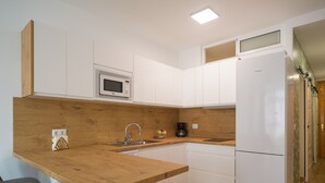 A modern kitchen with wooden countertops, a built-in microwave, a sink, and a refrigerator.