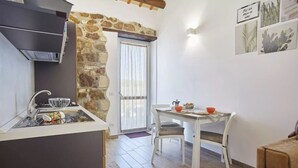 A compact kitchen with a stone wall, a dining area with a table and chairs, and a sofa in the corner.