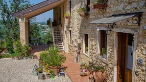 A stone building with a covered patio, outdoor seating, and potted plants.