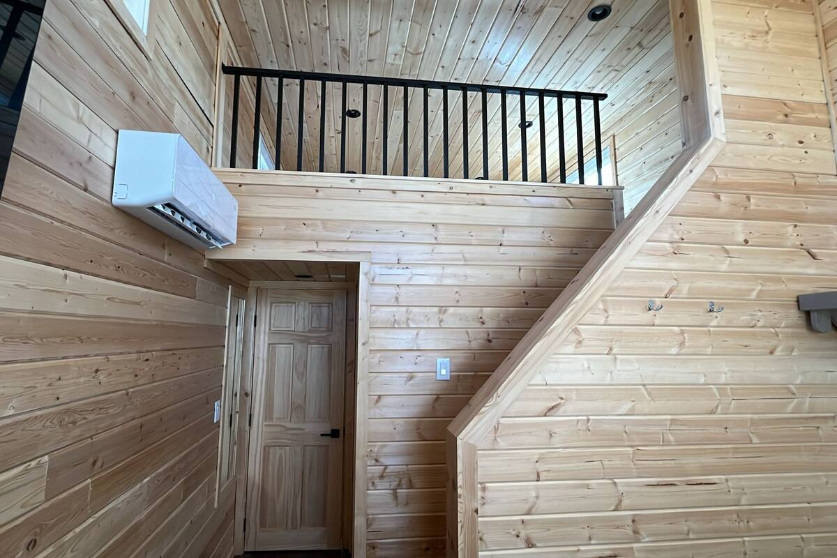 A wooden interior with a staircase leading to a balcony.