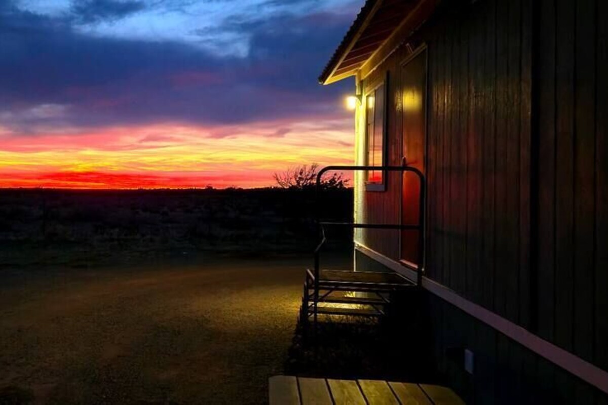 A building with a porch and a view of a sunset.