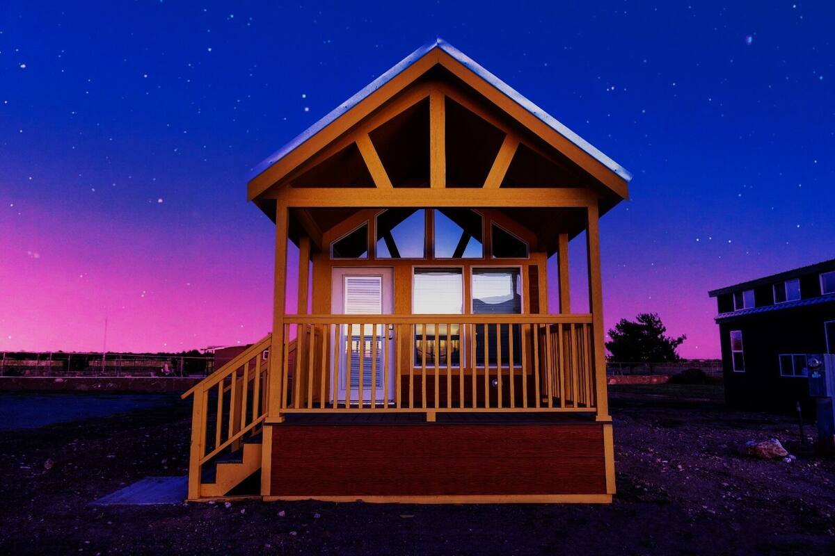 A wooden cabin with a balcony and a staircase leading to the entrance.
