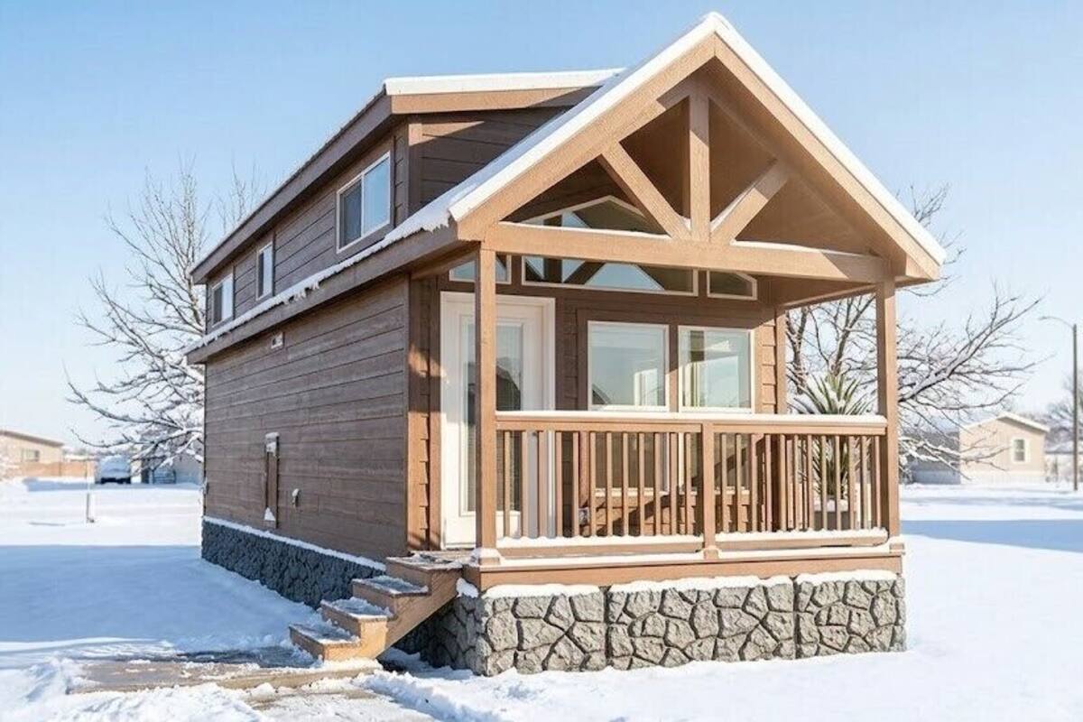 A wooden cabin with a stone foundation, a balcony, and a clear sky.