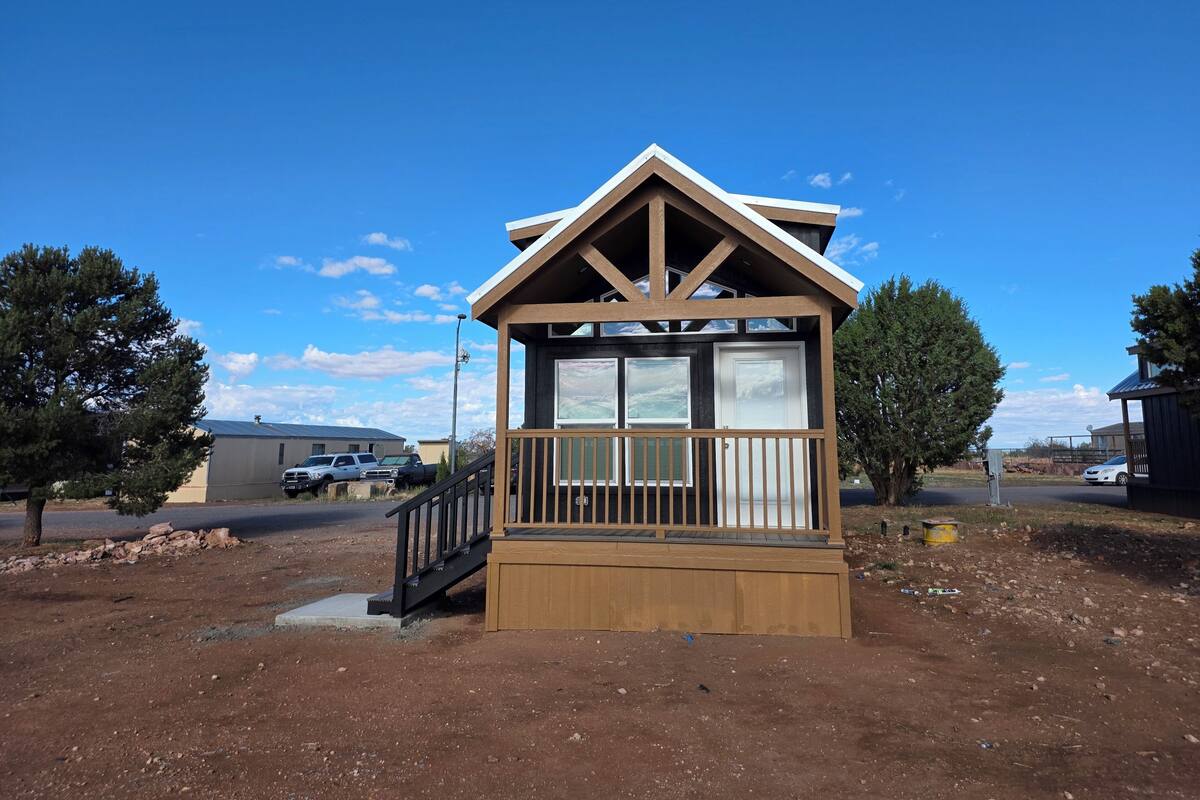 A small wooden cabin with a balcony, a covered porch, and a garage.