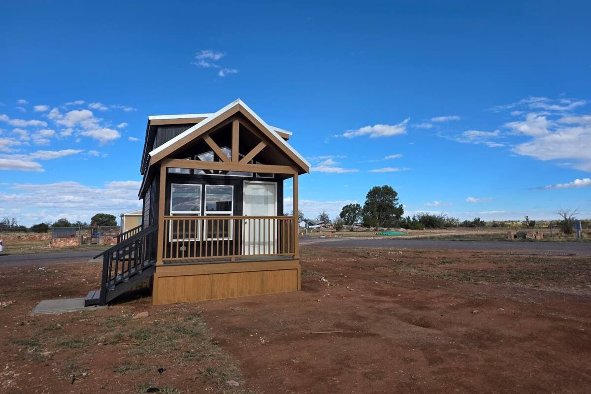 A small wooden cabin with a balcony, a staircase, and a clear view of the surrounding landscape.
