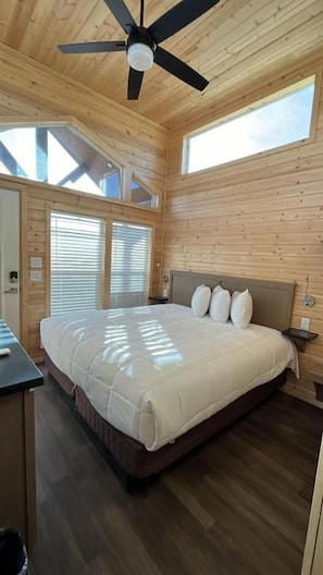 A bedroom with a bed, wooden walls, a ceiling fan, and skylights. - Grand Canyon Tiny Homes (Williams)