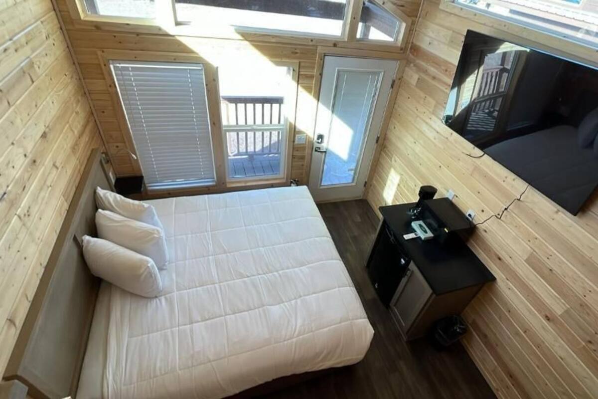 A compact bedroom with a bed, a small desk, and a television.