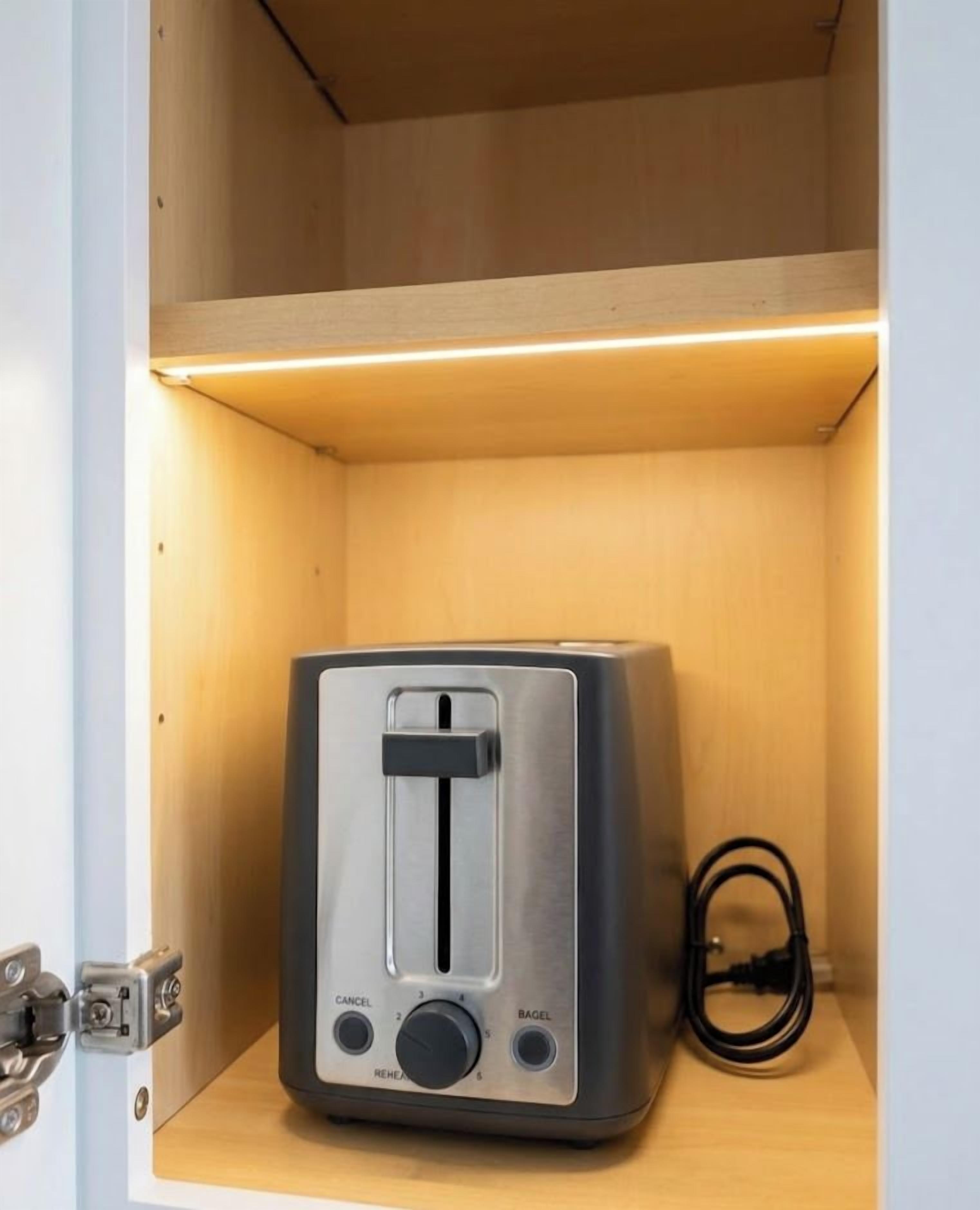 A toaster in a wooden cabinet with a cable.
