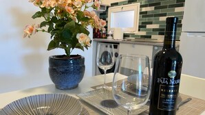A dining table with a bottle of wine, two wine glasses, and a potted plant.
