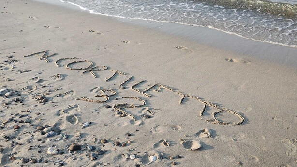 A beach with footprints and the word "NORTHEAST" written in the sand.