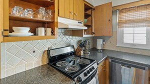 A kitchen with a black stove, wooden cabinets, and a dishwasher.