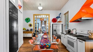 Eine moderne Küche mit Essbereich, ausgestattet mit einem Edelstahlkühlschrank, weißen Schränken und einer farbenfrohen Tischdecke mit Blumenmuster.
