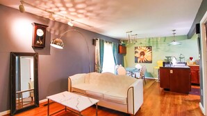 Ein Wohnzimmer mit einer Couch, einem Couchtisch, einer Uhr und einem Bild an der Wand.