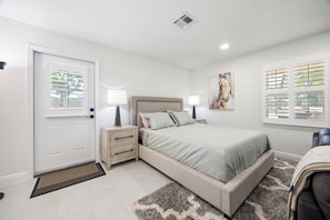 A bedroom with a bed, bedside tables, a door, and a window with blinds. - Large efficiency with WiFi, AC, W/D less than 1 minute from WEC!!! (Ocala)
