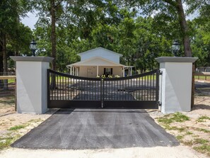 A gated entrance to a building with a white exterior and a covered porch. - Large efficiency with WiFi, AC, W/D less than 1 minute from WEC!!! (Ocala)