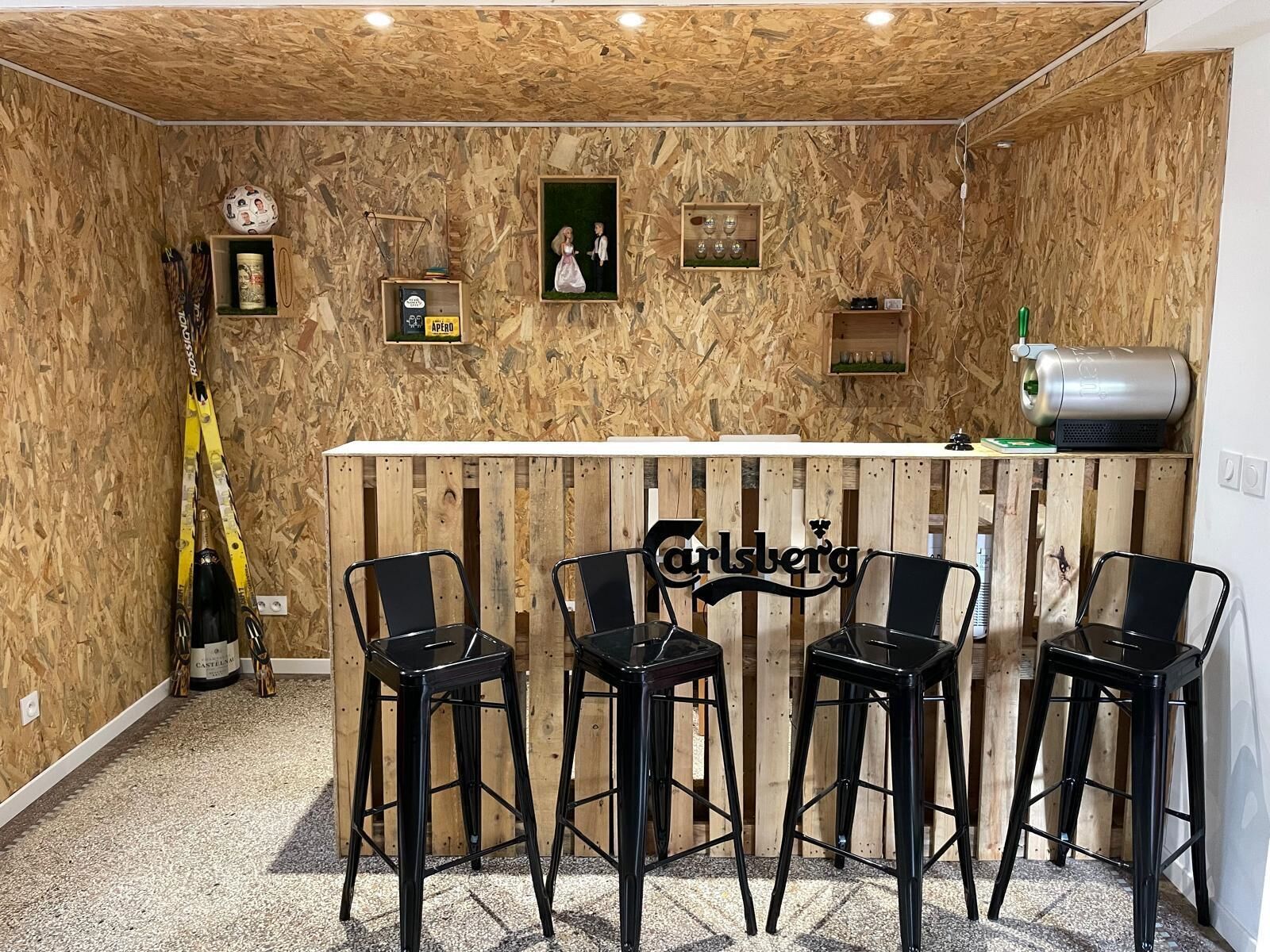 A bar area with a wooden backdrop, bar stools, and a sign reading "Carlsberg".