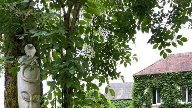A garden with a stone sculpture, flowering plants, and a building with ivy. - Large party house, family or EVJ/G Ideal for get-togethers. (Loupeigne)