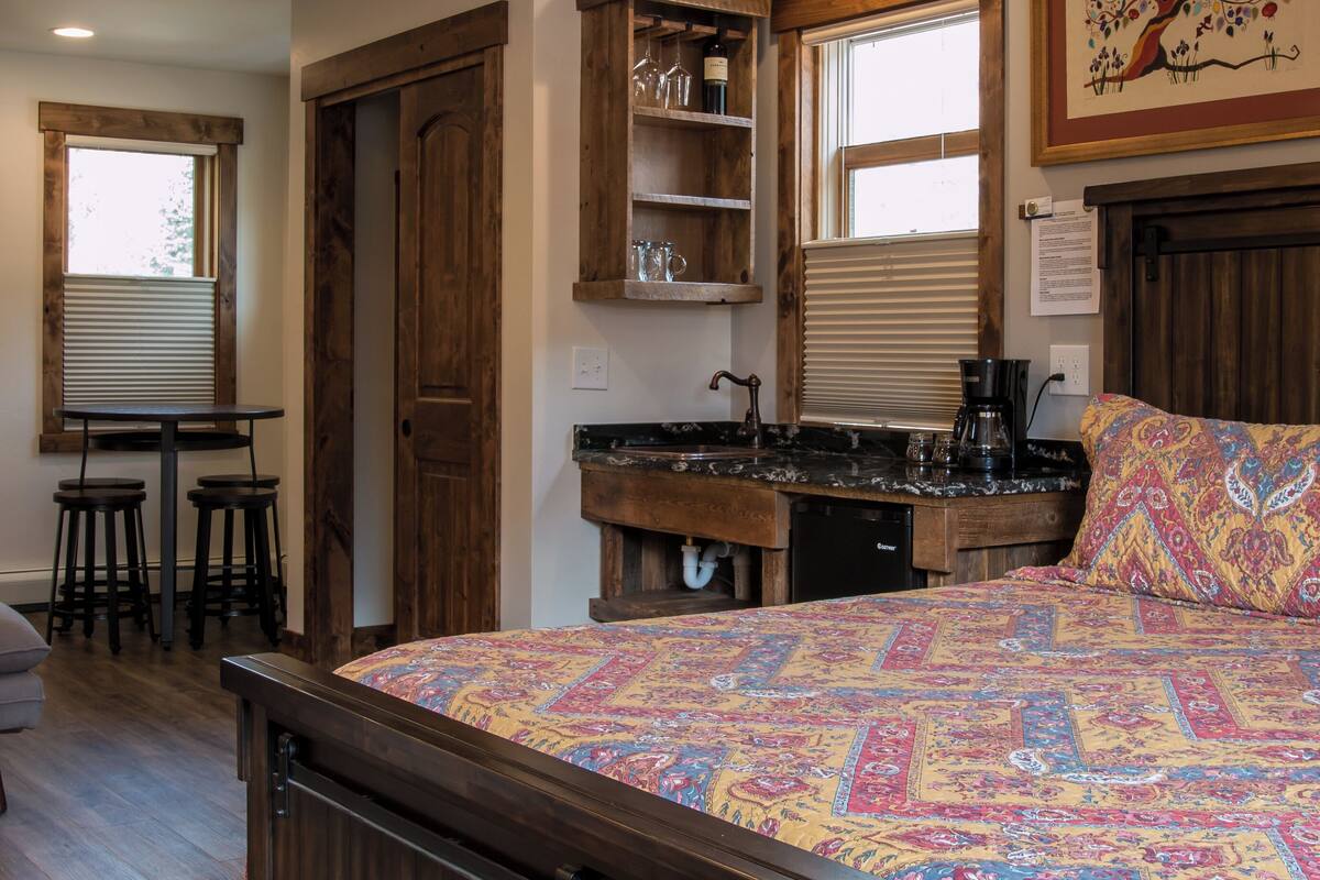 A bedroom with a bed, a desk, a chair, a window, and a ceiling fan.