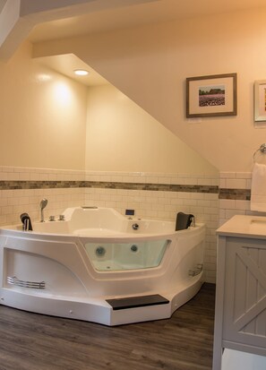 A modern bathroom with a freestanding bathtub, a tiled shower area, and a wooden floor.