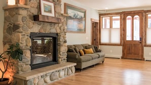 A stone fireplace with a built-in TV, a wooden bench, a sofa, and a potted plant. - Clear Creek Inn (Georgetown)