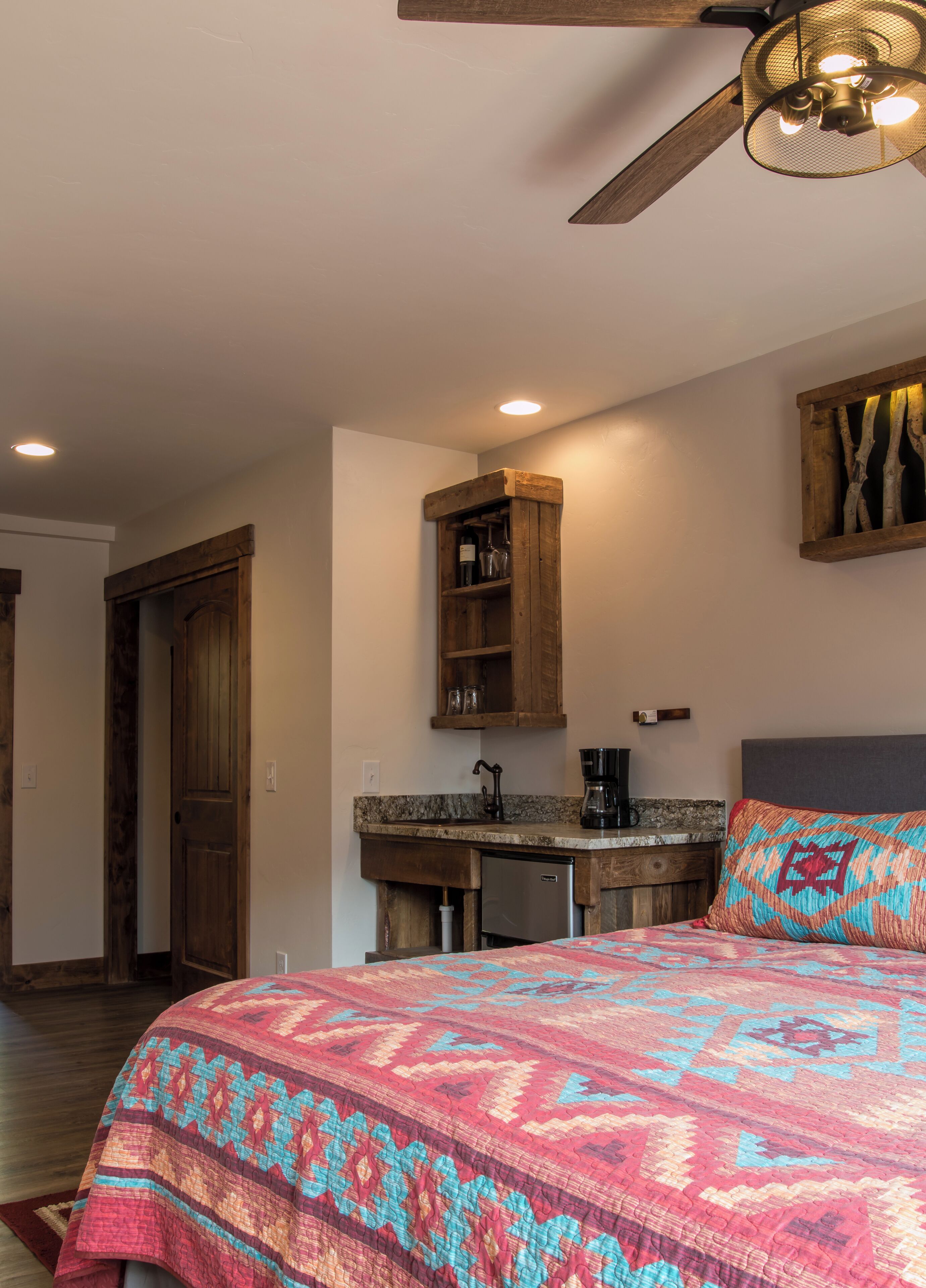 Ein Schlafzimmer mit Bett, Schreibtisch und Deckenventilator.