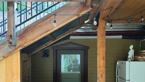 A wooden cabin with a kitchen area, a small dining table, and a staircase leading to an upper level. - Clear Creek Inn (Georgetown)