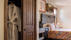 A bedroom with a wooden wardrobe, a bed with patterned bedding, a coffee maker, and a framed artwork on the wall. - Clear Creek Inn (Georgetown)