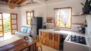 Eine kompakte Küche mit Kühlschrank, Spüle und Herd, Holzschränken sowie einem Essbereich mit Tisch und Stühlen.