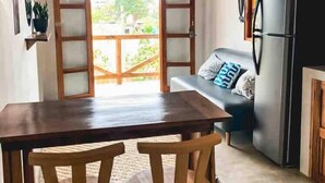 Eine kleine Küche mit Holztisch und -stühlen, einem schwarzen Kühlschrank und einer Glastür zum Außenbereich.