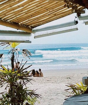 Escena de playa con una estructura de madera sobre la arena y olas del océano.