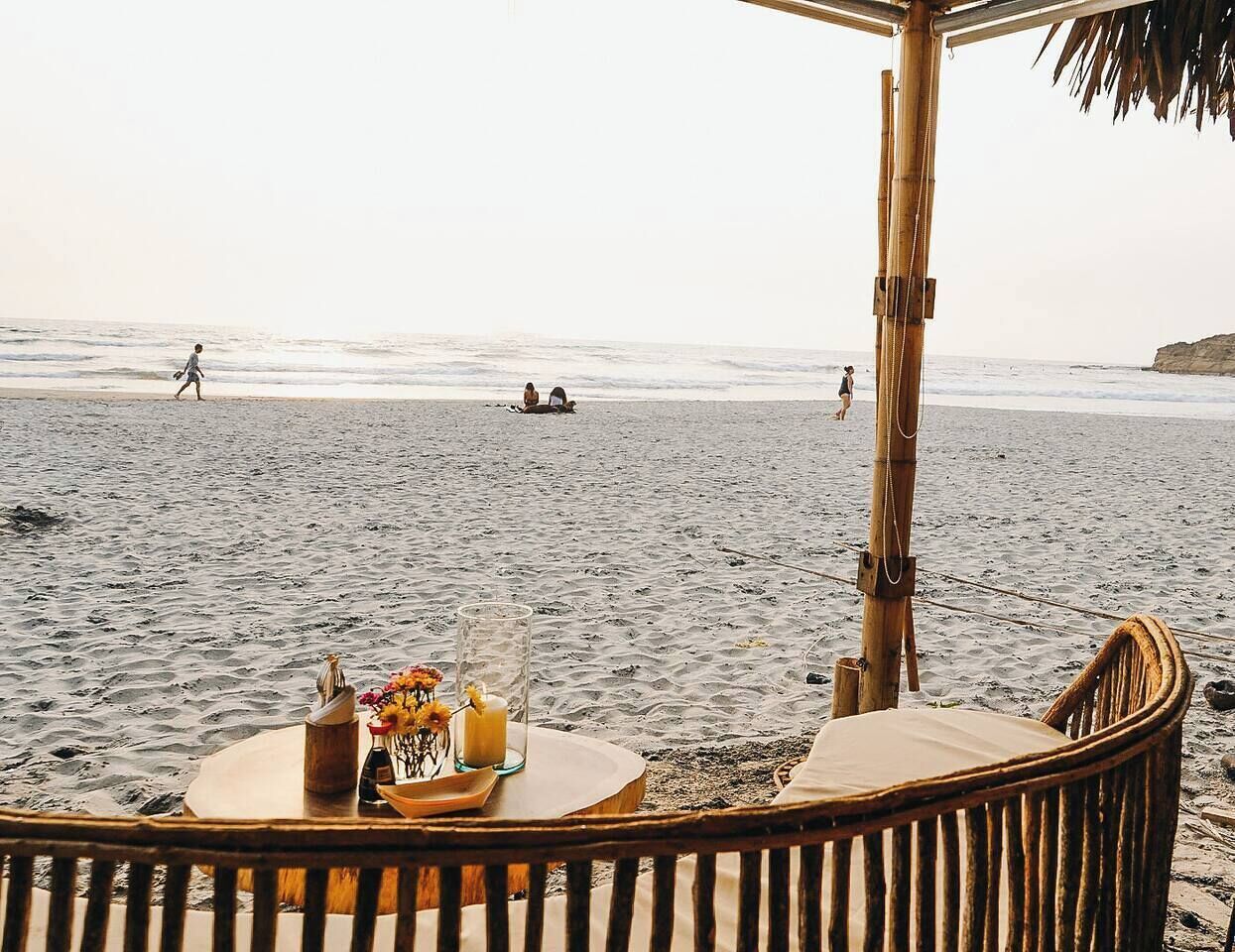 A beachside seating area with a table set for two, overlooking the ocean.