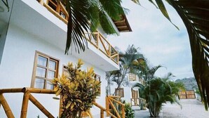A building with a white exterior, wooden balconies, and a paved walkway.